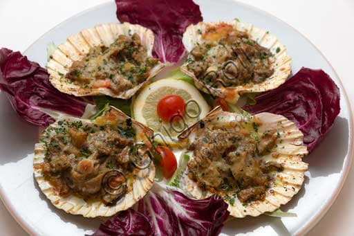 Dish of golden-brown scallops au gratin with porcini mushrooms in a ceramic baking tray.