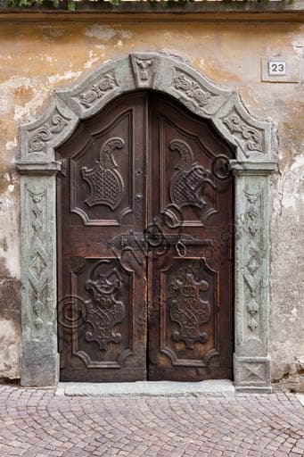 Old house wooden door with stone jamb of a historic dwelling in Bormio