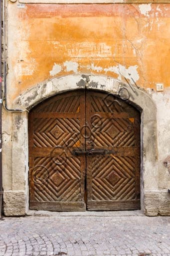 Antique wooden door of a historical house in Bormio, detail of wrought iron fixtures and solid wood.