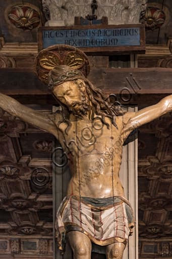 Detailed close-up of a 15th-century Gothic polychrome wooden crucifix, depicting the carved figure of Christ, highlighting the paint and wood texture.