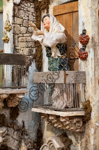 Detail of Sicilian Nativity scene by Ivano Vecchio: small wooden statue of a woman on a balcony