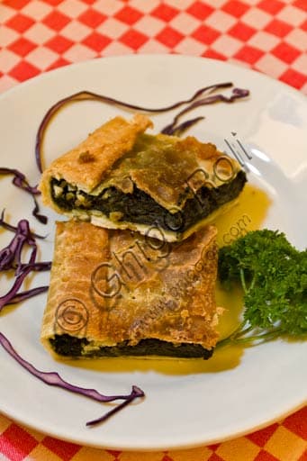 Traditional Erbazzone, a savory pie from Reggio Emilia Italy, with a cross-section showing chard and cheese filling.
