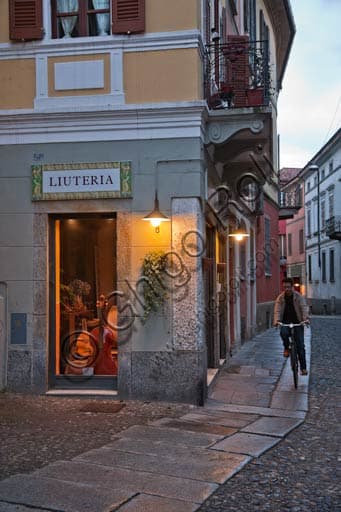 Photograph of a luthier's workshop on a Cremona square with a young man riding a bicycle past it