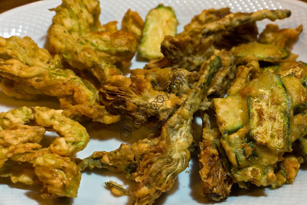 Traditional Tuscan fried vegetables including golden artichokes and zucchini, plated for serving.