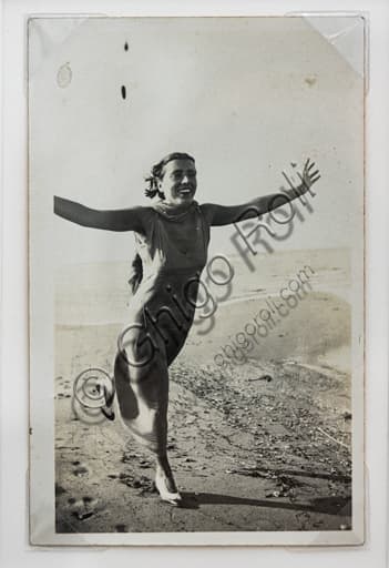 Black and white vintage photo by Marcello Dudovich: woman running on a beach with open arms, bromide silver gelatine print