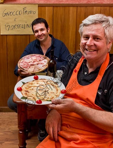 Inside Osteria La Carrozza in Piacenza with a cutting board of typical cold-cuts and bortellina