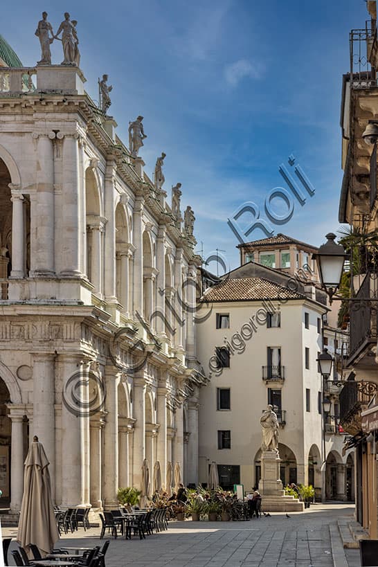 Statue of Andrea Palladio in the piazzetta with outdoor cafe tables and view of the Palladian Basilica in Vicenza, Italy
