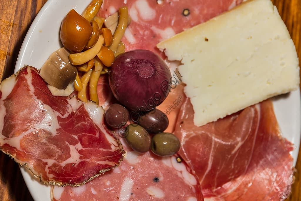 Assortment of typical Tuscan products: cold cuts, olives in brine and Pecorino cheese on a wooden board.