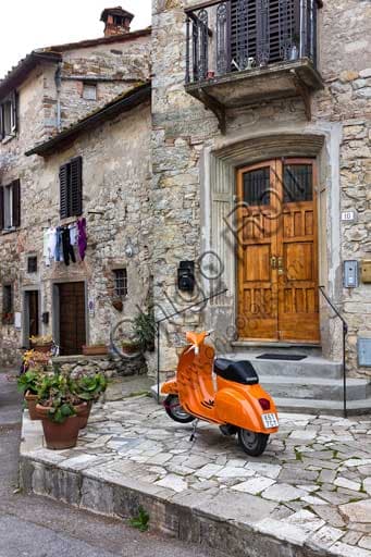 Fotografia dello scorcio di Radda in Chianti con uno scooter Vespa parcheggiato in una via lastricata