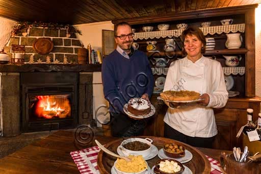 Table display with traditional Aosta Valley dishes: polenta, venison stew, chestnuts, and cakes at La Capanna di Carla restaurant in Gressoney.