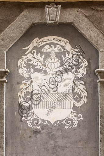 Heraldic coat of arms in stone or metal on the façade of a historic hotel in Bormio