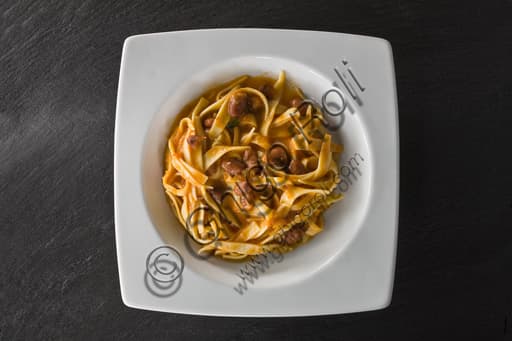 Plate of tagliatelle alla bolognese with traditional ragù, served on a wooden table.