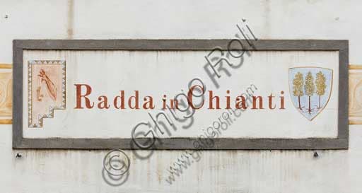 Tascione ceramico con il nome del paese Radda in Chianti affisso sulla facciata di un edificio storico nel Chianti