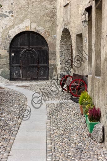 Photograph of the characteristic cobbled street in Bormio old town, with stone buildings and frescoed facades