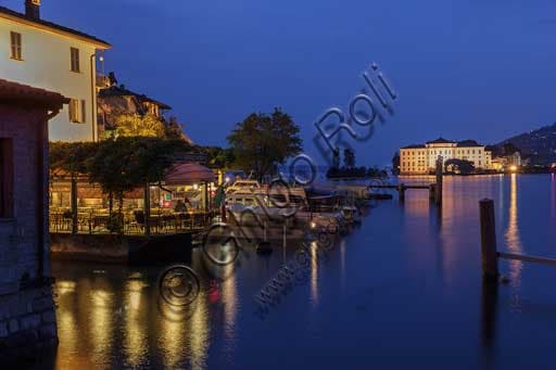 Night view of the lakefront and pier at Isola Pescatori on Lake Maggiore, with Isola Bella and the illuminated Borromeo Palace in the background.