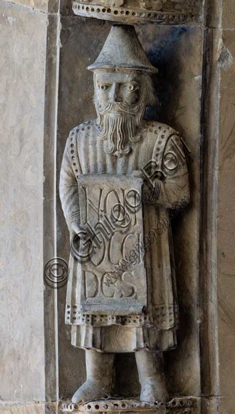 Fidenza, Duomo (Cattedrale di San Donnino), facciata, portale maggiore: dettaglio dell’archivolto con una delle figure di profeti raffiguranti I comandamenti con l’iscrizione: NON / OCCI/DES = Non ucciderai (Es 20, 13).Opera di Benedetto Antelami e bottega.