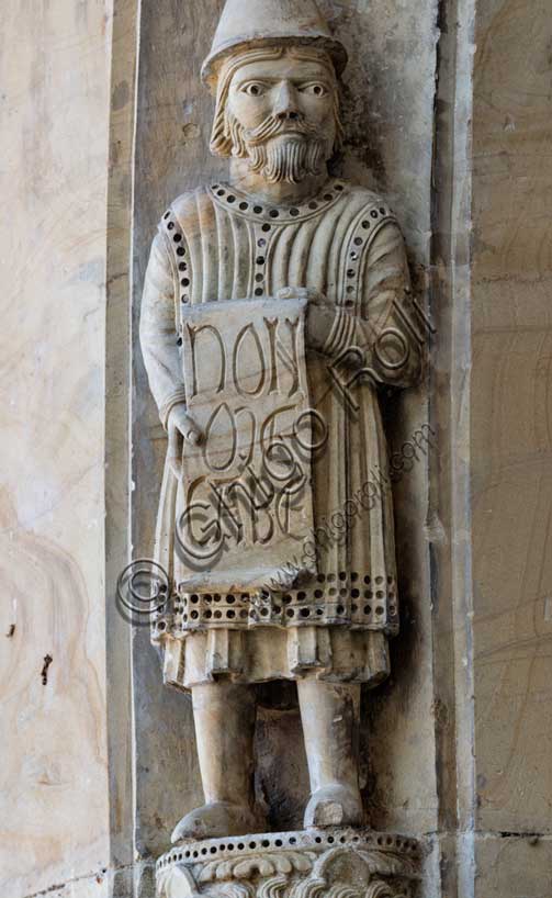 Fidenza, Duomo (Cattedrale di San Donnino), facciata, portale maggiore: dettaglio dell’archivolto con una delle figure di profeti raffiguranti I comandamenti con l’iscrizione: NON / M[O]E/CABE[RIS] = Non fornicherai (Es. 20, 14).Opera di Benedetto Antelami e bottega.