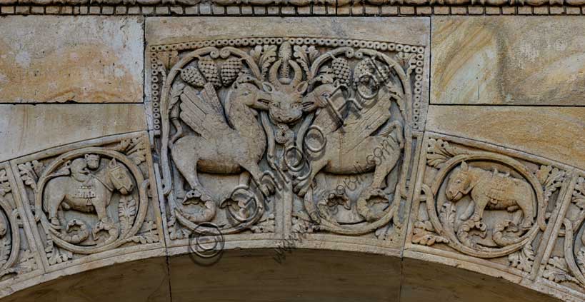 Fidenza, Duomo (Cattedrale di San Donnino), portale destro: dettaglio dell’arco del protiro.Particolare di due creature fantastiche con una maschera cornuta dal cui ghigno esce un serpente, chiaro riferimento a Satana.Opera di Benedetto Antelami e bottega.