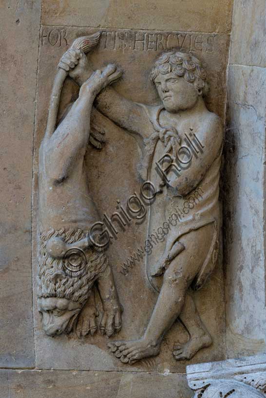 Fidenza, Duomo (Cattedrale di S. Donnino), facciata, portale di destra, interno del protiro: “Ercole mostra il leone nemeo da lui ucciso”,  bassorilievo di Benedetto Antelami e bottega.