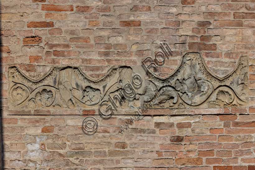 Fidenza, Duomo (Cattedrale di San Donnino), abside: frammento architettonico decorativo della parte superiore d’una quadrifora con archi acuti. Tra foglie d’acanto e un tralcio di vite si riconosce una “Annunciazione”.