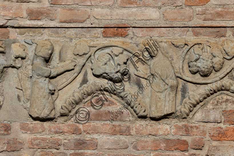 Fidenza, Duomo (Cattedrale di San Donnino), abside: frammento architettonico decorativo della parte superiore d’una quadrifora con archi acuti. Tra foglie d’acanto e un tralcio di vite si riconosce una “Annunciazione”.