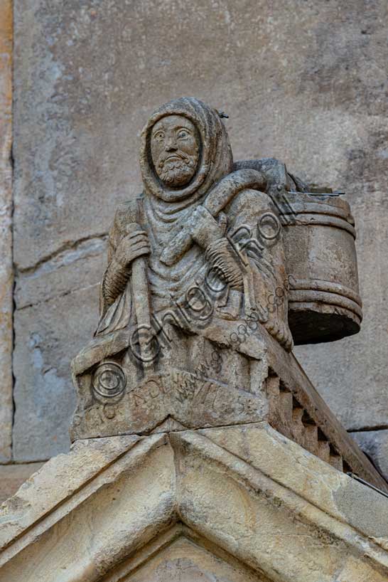 Fidenza, Duomo (Cattedrale di San Donnino), acroterio del portale destro: “Raimondinus vilis”, il Povero Raimondino. In questa figura viene tradizionalmente riconosciuto  San Raimondino Zanfogni, detto Palmerio, di Piacenza (1140 – 27 luglio 1200), un laico che sarebbe stato pellegrino in Terrasanta (da qui il soprannome) e poi a San Giacomo di Campo Stella. Tornato a Piacenza avrebbe assistito e difeso i poveri della sua città e avrebbe fondato un ospedale. 