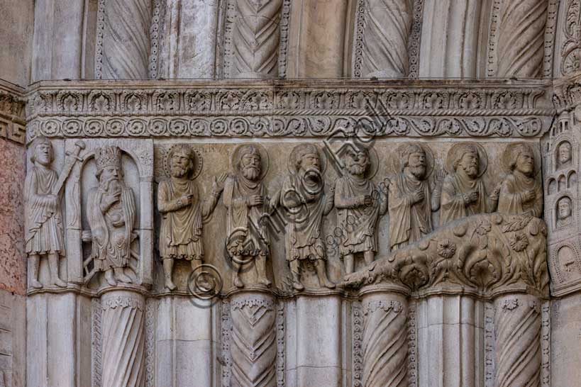 Fidenza, duomo (Cattedrale di San Donnino), facciata, portale maggiore: dettaglio dell’archivolto con “Storie di San Donnino”.L'imperatore Massimiano si accarezza la barba (meditando la vendetta). Il santo fugge assieme ai suoi compagni (Donnino è il primo da sinistra, con l'aureola abbellita da un cerchio di piccoli fori).Opera di  Benedetto Antelami e bottega.