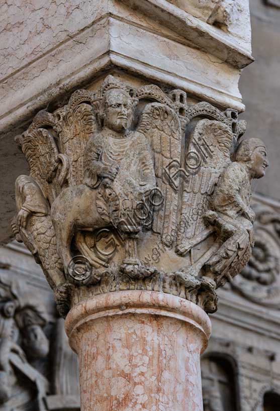 Fidenza, Duomo (Cattedrale di San Donnino), facciata, portale maggiore, protiro: il capitello di destra con “i Quattro Evangelisti”. Al centro “S. Marco”, che reca, incisa sul cartiglio l’iscrizione a lettere capitali: V[O] / X / CLA / MANTIS (Vox Clamantis (Mc 1,3) = Voce di chi chiama…). Opera di Benedetto Antelami e bottega.