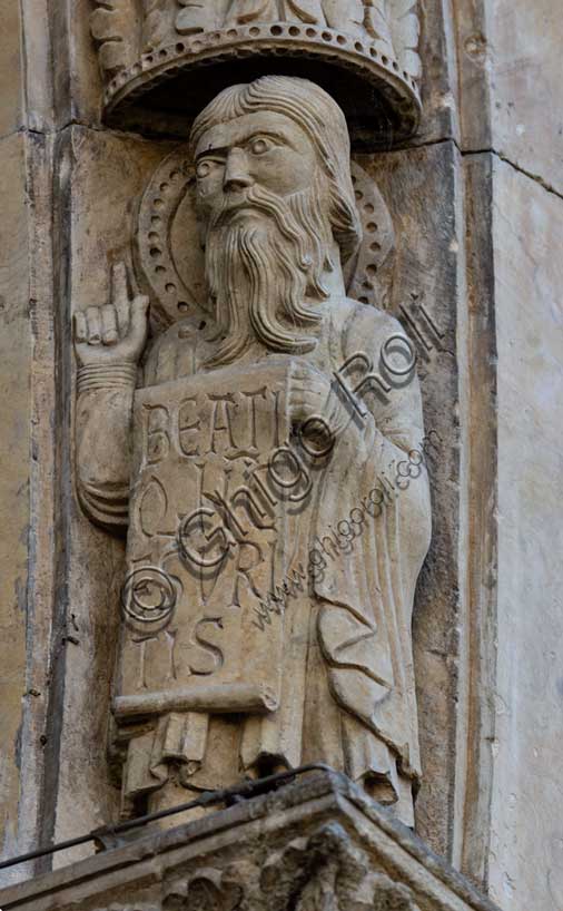 Fidenza, Duomo (Cattedrale di San Donnino), facciata, portale maggiore: dettaglio dell’archivolto con “Allegorie delle Beatitudini”. Apostolo con l’iscrizione:   BEATI / Q[VI] N[VN]C / ESVRI/TIS = Beati quelli che hanno fame (Lc 6, 21). Opera di Benedetto Antelami e bottega.