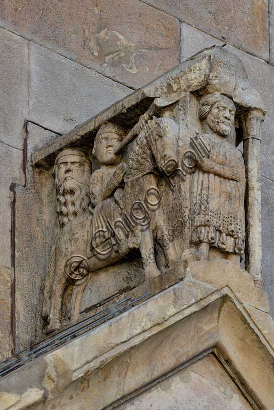 Fidenza, duomo (Cattedrale di San Donnino), portale sinistro, timpano. Nell’acroterio sul timpano, é raffigurato un personaggio, probabilmente Oberto II Pallavicino condottiero posto da Federico II di Svevia alla guida della città dal 1249 al 1268. Al suo fianco due suonatori di tromba a cavallo.Opera di Benedetto Antelami e bottega.