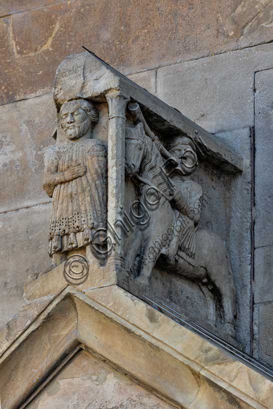 Fidenza, duomo (Cattedrale di San Donnino), portale sinistro, timpano. Nell’acroterio sul timpano, é raffigurato un personaggio, probabilmente Oberto II Pallavicino condottiero posto da Federico II di Svevia alla guida della città dal 1249 al 1268. Al suo fianco due suonatori di tromba a cavallo.Opera di Benedetto Antelami e bottega.