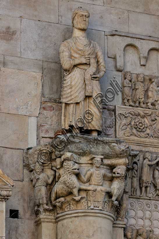 Fidenza, duomo (Cattedrale di San Donnino), sculture tra il portale maggiore e quello di sinistra: il capitello con “Daniele nella fossa dei leoni”, sormontato dalla statua con “San Simone Apostolo che mostra la via di Roma ai pellegrini”; 