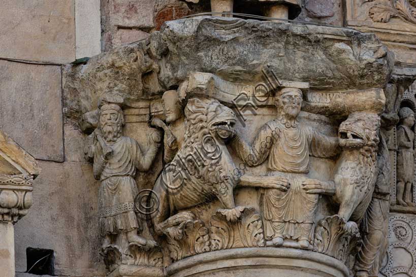 Fidenza, duomo (Cattedrale di San Donnino), sculture tra il portale maggiore e quello di sinistra. Particolare del semicapitello con “Daniele nella fossa dei leoni”. Il semicapitello figurato che raffigura nella parte frontale la scena biblica – di simbologia cristologica – del profeta Daniele che gettato nella fossa è attorniato dai leoni ammansiti. Sua lato destro del semicapitello è raffigurato il profeta Abacuc con il cibo per Daniele e sul lato sinistro l’angelo che lo portò (Dn 14,33-38). Sull’abaco del semicapitello è incisa a lettere capitali l’iscrizione: […]C DANIEL IVSTUS INLA EST CV LEONV[M] ([Abacu]c . Daniel iustus in lacu est cum leonum).Opera di Benedetto Antelami e bottega.