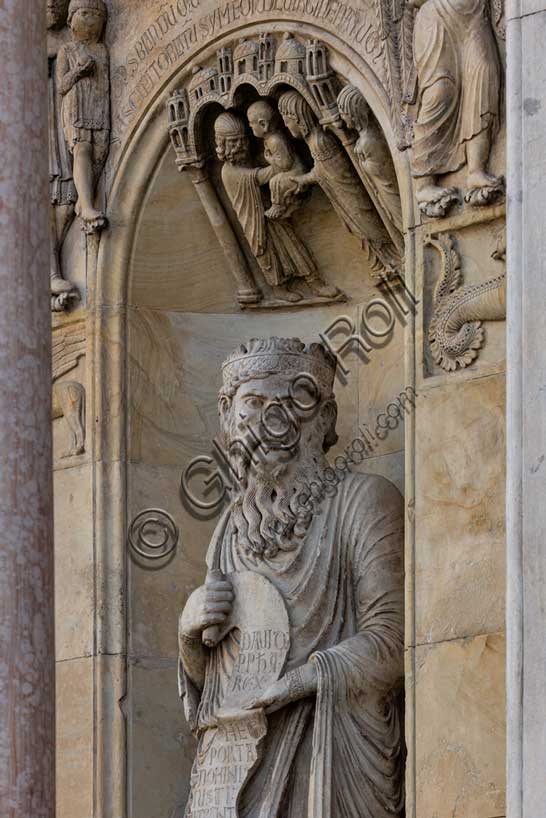 Fidenza, duomo (Cattedrale di San Donnino), sculture tra il portale maggiore e quello di sinistra: la nicchia con il “Re David” di Benedetto Antelami.Il profeta sorregge un cartiglio sul quale si legge la seguente iscrizione a lettere capitali: DAUID / PPHA / REX / HEC / PORTA / DOMINI / IUSTI: / INTRANT PEREAM (David Propheta Rex – Hec porta Domini iusti intrant per eam [Salmo 118 (117),20]).Lo sguardo di Re David è rivolto a chi entra nella cattedrale dal portale maggiore.