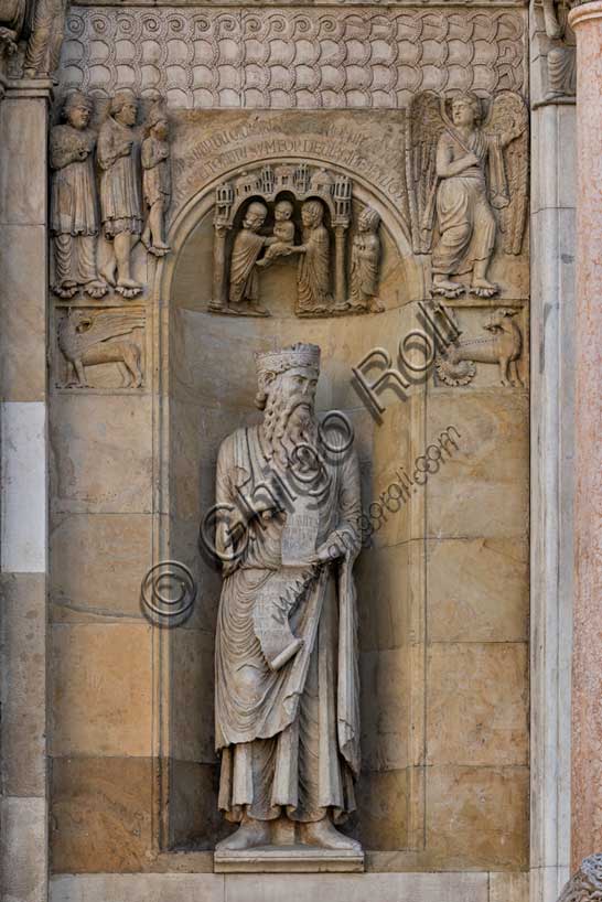 Fidenza, duomo (Cattedrale di San Donnino), sculture tra il portale maggiore e quello di sinistra: la nicchia con il “Re David” di Benedetto Antelami.Il profeta sorregge un cartiglio sul quale si legge la seguente iscrizione a lettere capitali: DAUID / PPHA / REX / HEC / PORTA / DOMINI / IUSTI: / INTRANT PEREAM (David Propheta Rex – Hec porta Domini iusti intrant per eam [Salmo 118 (117),20]).Nella calotta della nicchia è la Presentazione di Gesù al Tempio. Ai lati sono due formelle con le figura di un grifo e di un capricorno; al di sopra di esse si osserva un bassorilievo raffigurante verosimilmente un Angelo che mostra la via per Roma ad una famiglia di pellegrini ricchi. 