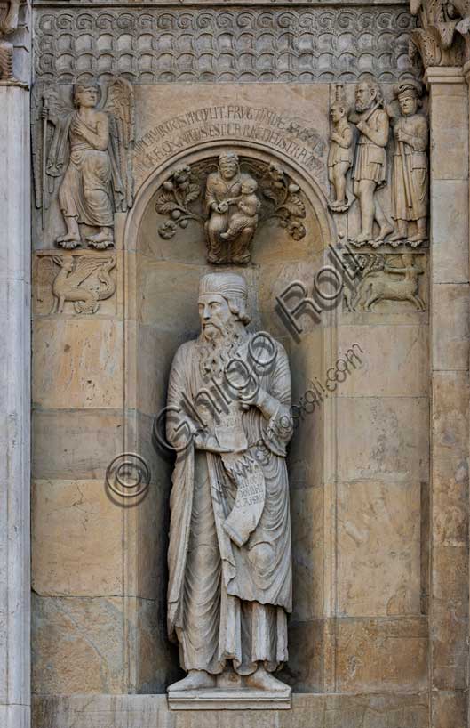 Fidenza, duomo (Cattedrale di San Donnino):“Il Profeta Ezechiele” di Benedetto Antelami.Il profeta sorregge un cartiglio che rimanda al significato della chiesa come "Porta del Cielo"; vi si legge: Ezechiel Propheta; vidi portam in domo Domini clausam (Ezechiele Profeta; ho visto chiusa la porta nella casa del Signore). Nella calotta della nicchia è posto un bassorilievo raffigurante una Madonna col Bambino circondata da racemi di fiori e di frutta sormontata da una scritta che ne spiega il significato teologico.Ai lati della nicchia, sempre in simmetria con la parte sinistra della facciata, vediamo due formelle rappresentanti un'arpia e un centauro che colpisce un cervo, e, più in alto, la figura di un Angelo intento verosimilmente ad indicare ad una famiglia di pellegrini poveri la strada della Via Francigena.Sopra una fascia ornata con motivi geometrici é il bassorilievo del “Miracolo della donna gravida”.