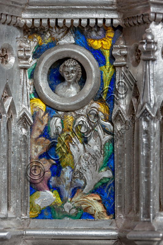 Florence, Museum of the Opera del Duomo (Museum of Florence Cathedral of Santa Maria del Fiore): “the silver altar of St. John's Treasure” (1367 - 1483), by florentine masters.Front of the dossal: upper detail of the fifth pillar with enamel floral motifs and head within clypeus.