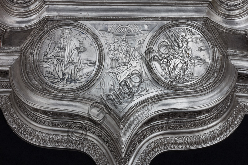 Firenze, Museo dell'Opera del Duomo (Santa Maria del Fiore): “La croce del tesoro di S. Giovanni: il recto”. Splendido esempio di oreficeria rinascimentale, scolpita in lamina d’argento, cesellata e smaltata da Betto di Francesco Betti, Antonio del Pollaiolo e Miliano di Domenico Dei tra il 1457 e il 1459 circa. Venne commissionata a completamento dell’altare d’argento. La Croce-ostensorio è composta da tre parti principali distinte: il Crocifisso, il fusto e la base. Particolare del basamento con, a sinistra, medaglione che raffigura “la Fede”, che regge in una mano il calice e la patena, mentre nell'altra brandisce una croce. Al centro raffigurazione di “Mosè” e a destra medaglione con angelo.