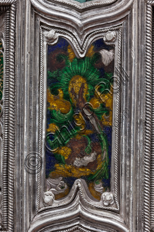 Firenze, Museo dell'Opera del Duomo (Santa Maria del Fiore): “La croce del tesoro di S. Giovanni: il verso”. Particolare con decorazione floreale.La Croce è uno splendido esempio di oreficeria rinascimentale, scolpita in lamina d’argento, cesellata e smaltata da Betto di Francesco Betti, Antonio del Pollaiolo e Miliano di Domenico Dei tra il 1457 e il 1459 circa. Venne commissionata a completamento dell’altare d’argento. La Croce-ostensorio è composta da tre parti principali distinte: il Crocifisso, il fusto e la base. 