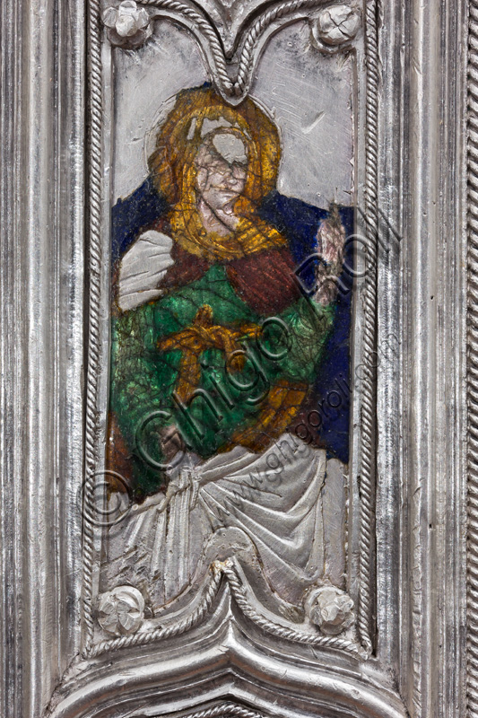 Firenze, Museo dell'Opera del Duomo (Santa Maria del Fiore): “La croce del tesoro di S. Giovanni: il verso”. Particolare con santa.La Croce è uno splendido esempio di oreficeria rinascimentale, scolpita in lamina d’argento, cesellata e smaltata da Betto di Francesco Betti, Antonio del Pollaiolo e Miliano di Domenico Dei tra il 1457 e il 1459 circa. Venne commissionata a completamento dell’altare d’argento. La Croce-ostensorio è composta da tre parti principali distinte: il Crocifisso, il fusto e la base. 