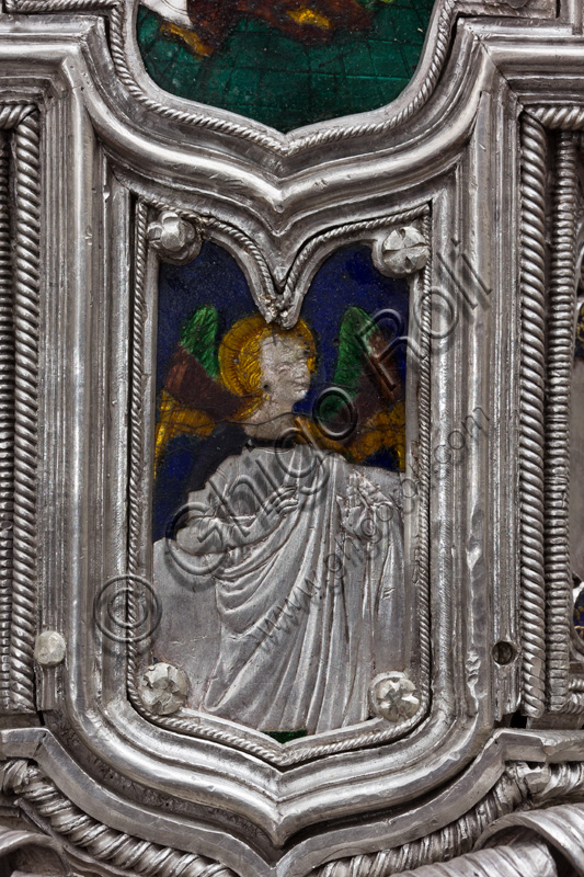 Firenze, Museo dell'Opera del Duomo (Santa Maria del Fiore): “La croce del tesoro di S. Giovanni: il recto”.Particolare della parte superiore con figura di angelo.La Croce è uno splendido esempio di oreficeria rinascimentale, scolpita in lamina d’argento, cesellata e smaltata da Betto di Francesco Betti, Antonio del Pollaiolo e Miliano di Domenico Dei tra il 1457 e il 1459 circa. Venne commissionata a completamento dell’altare d’argento. La Croce-ostensorio è composta da tre parti principali distinte: il Crocifisso, il fusto e la base. 