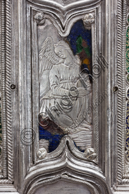 Firenze, Museo dell'Opera del Duomo (Santa Maria del Fiore): “La croce del tesoro di S. Giovanni: il recto”.Particolare della parte superiore con figura di angelo.La Croce è uno splendido esempio di oreficeria rinascimentale, scolpita in lamina d’argento, cesellata e smaltata da Betto di Francesco Betti, Antonio del Pollaiolo e Miliano di Domenico Dei tra il 1457 e il 1459 circa. Venne commissionata a completamento dell’altare d’argento. La Croce-ostensorio è composta da tre parti principali distinte: il Crocifisso, il fusto e la base. 