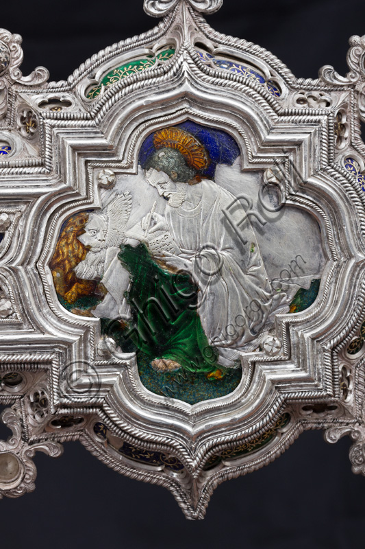 Florence, Museum of the Opera del Duomo (Museum of Florence Cathedral of Santa Maria del Fiore): “The Cross of the Treasure of St. John: the verso.”Detail of “St. Mark the Evangelist and the lion”.The Cross  is a splendid example of Renaissance jewelery, sculpted in silver foil, chiseled and enameled by Betto di Francesco Betti, Antonio del Pollaiolo and Miliano di Domenico Dei between 1457 and 1459 approximately. It was commissioned to complete the silver altar. The Cross-monstrance is made up of three distinct main parts: the Crucifix, the stem and the base. 