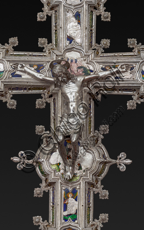 Florence, Museum of the Opera del Duomo (Museum of Florence Cathedral of Santa Maria del Fiore): “The Cross of the Treasure of St. John: the verso.”Detail with “statue of crucified Christ”.The Cross  is a splendid example of Renaissance jewelery, sculpted in silver foil, chiseled and enameled by Betto di Francesco Betti, Antonio del Pollaiolo and Miliano di Domenico Dei between 1457 and 1459 approximately. It was commissioned to complete the silver altar. The Cross-monstrance is made up of three distinct main parts: the Crucifix, the stem and the base. 