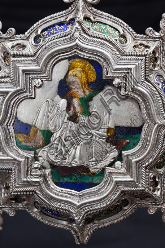 Firenze, Museo dell'Opera del Duomo (Santa Maria del Fiore): “La croce del tesoro di S. Giovanni: il recto”.Particolare della parte superiore con figura di santa o Madonna.La Croce è uno splendido esempio di oreficeria rinascimentale, scolpita in lamina d’argento, cesellata e smaltata da Betto di Francesco Betti, Antonio del Pollaiolo e Miliano di Domenico Dei tra il 1457 e il 1459 circa. Venne commissionata a completamento dell’altare d’argento. La Croce-ostensorio è composta da tre parti principali distinte: il Crocifisso, il fusto e la base. 