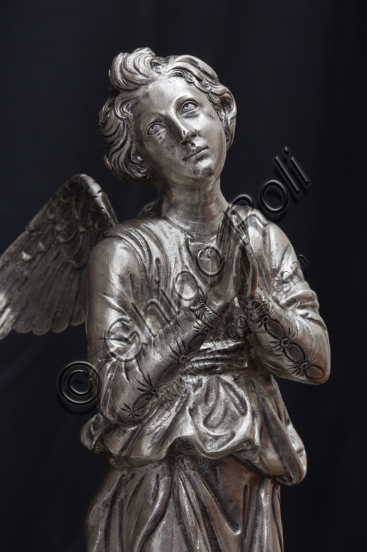 Firenze, Museo dell'Opera del Duomo (Santa Maria del Fiore): “La croce del tesoro di S. Giovanni: il recto”.Particolare: statua di angelo.La croce è uno splendido esempio di oreficeria rinascimentale, scolpita in lamina d’argento, cesellata e smaltata da Betto di Francesco Betti, Antonio del Pollaiolo e Miliano di Domenico Dei tra il 1457 e il 1459 circa. Venne commissionata a completamento dell’altare d’argento. La Croce-ostensorio è composta da tre parti principali distinte: il Crocifisso, il fusto e la base. 