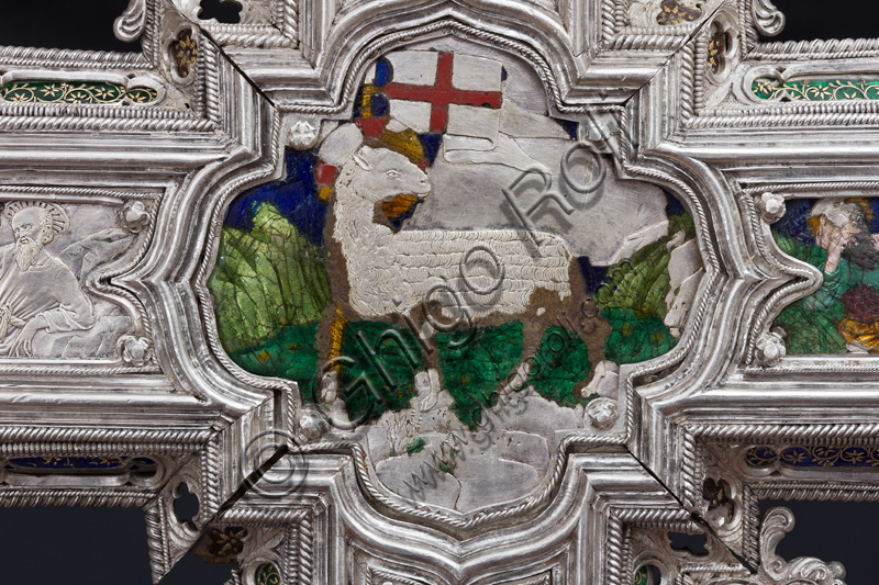 Florence, Museum of the Opera del Duomo (Museum of Florence Cathedral of Santa Maria del Fiore): “The Cross of the Treasure of St. John: the verso.”Detail of “Aguns Dei”.The Cross  is a splendid example of Renaissance jewelery, sculpted in silver foil, chiseled and enameled by Betto di Francesco Betti, Antonio del Pollaiolo and Miliano di Domenico Dei between 1457 and 1459 approximately. It was commissioned to complete the silver altar. The Cross-monstrance is made up of three distinct main parts: the Crucifix, the stem and the base. 