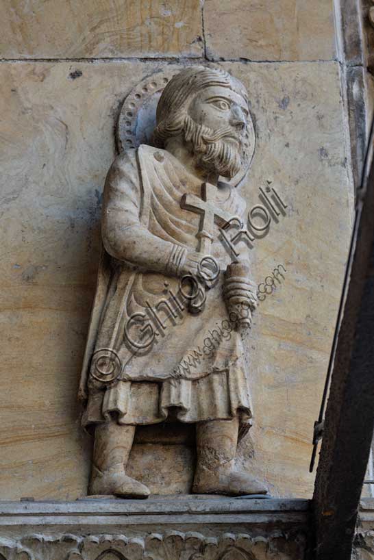 Fidenza, Duomo (Cattedrale di San Donnino), facciata, portale maggiore: dettaglio interno dell’archivolto con apostolo con una croce in mano in cammino verso l’esterno.Opera di Benedetto Antelami e bottega.