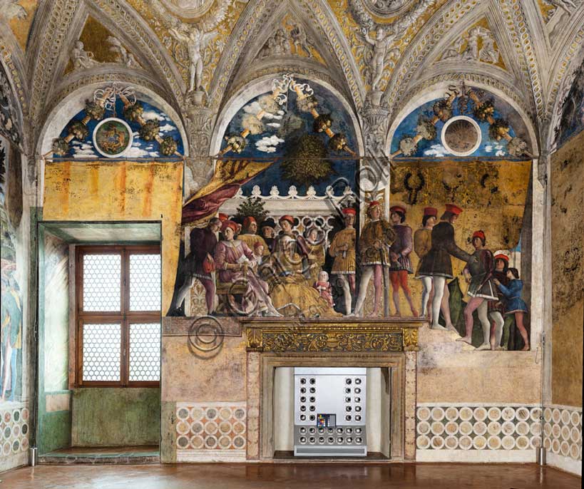 Ducal Palace: north-west wall of the “Bridal Chamber or Camera Picta", which is a room located in the north-east tower of the Castle of San Giorgio in Mantua. It is famous for the cycle of frescoes that covers its walls, a masterpiece by Andrea Mantegna, created between 1465 and 1474.This wall represents “The Court” of Ludovico II Gonzaga. On the left, under the opened curtain, Ludovico sits while a secretary (perhaps Marsilio Andreasi or Raimondo Lupi di Soragna) hands him a letter. We see Rubino, Marquis Ludovico's favorite dog and symbol of loyalty, crouching. To her right, the only other person seated, is the Marquis's wife, Barbara of Brandenburg with a little girl, perhaps the youngest daughter Paola who seems to be offering her an apple. Behind Ludovico we can recognize the third-born Gianfrancesco standing, holding his hands on the shoulders of a child, perhaps the prothonotary Ludovicino. The man with the black hat is Vittorino da Feltre, tutor of the marquis and his children.Behind his mother stands Rodolfo near a woman, probably Barbarina Gonzaga. The woman behind Barbarina is perhaps a nurse of the Gonzaga house or, as some scholars maintain, Paola Malatesta, mother of Ludovico II, in monastic dress. In the first profile in the background from the left we recognize the portrait of Leon Battista Alberti. Below is Lucia, “The Court” dwarf. Standing in front of one of the fake pilasters is the probable portrait of Niccolò d'Este.In the right sector, seven courtiers, passing in front of the closed curtain, approach the family. The general theme of the Camera Picta is a political-dynastic celebration of the entire family of Ludovico II Gonzaga.